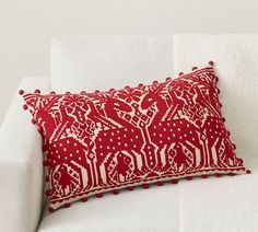 a red and white pillow sitting on top of a white couch