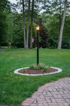 a lamp post with an american flag on it in the middle of a grassy area