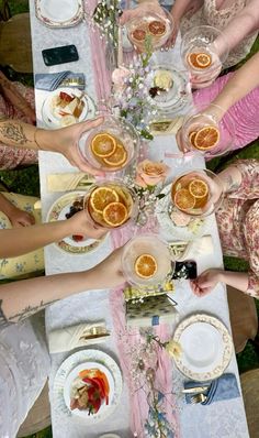 a group of people sitting at a table with plates and cups filled with orange slices