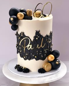 a black and white cake with gold decorations on it's top, sitting on a plate