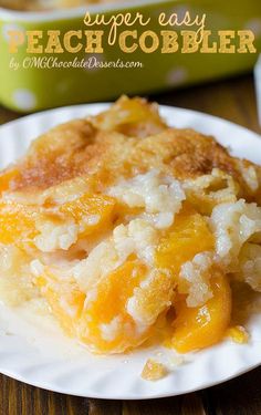 a slice of peach cobbler on a white plate next to a green casserole dish