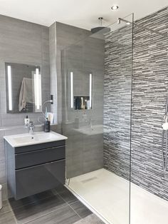 a bathroom with a glass shower door, sink and toilet next to a mirror on the wall