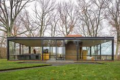 the glass house is surrounded by trees and grass