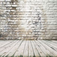 an empty wooden floor in front of a brick wall