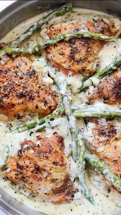 chicken with asparagus and cream sauce in a silver pan on a white surface