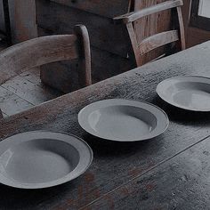 three empty plates sit on top of a wooden table