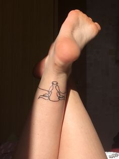 a woman's legs with a small tattoo on her left leg, and a cat sitting on the floor