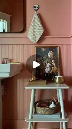 a bathroom with pink walls and a white table in front of a mirror on the wall