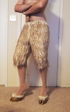 a man with his arms crossed standing in front of a door wearing furry shorts and slippers