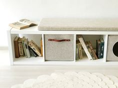 a white bench with books and magazines on it next to a book shelf filled with books