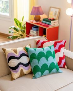 three colorful pillows on a white couch in a living room