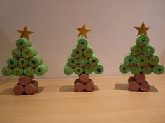 three small christmas trees made out of buttons and wood logs with gold stars on top