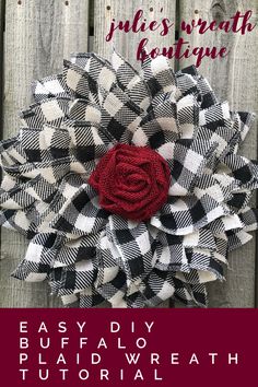 a black and white checkered wreath with a red rose in the center on a wooden fence