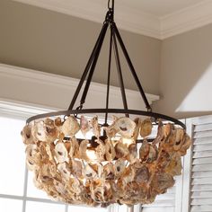 a chandelier with shells hanging from it's centerpiece in front of a window