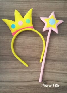 a pair of yellow and pink princess crowns on top of a wooden table next to a toothbrush