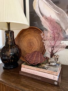 a table with two vases and books on it next to a lamp, painting