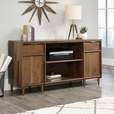 a wooden cabinet with drawers and a clock on the wall above it in a living room