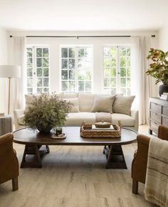 a living room with couches, chairs and a coffee table in front of a window