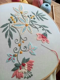 a close up of a embroidery on a table with some balls of yarn in the background