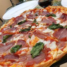 a pizza sitting on top of a pan covered in cheese and toppings next to a glass of wine