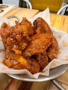 a bowl filled with fried chicken on top of a wooden table