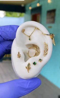 a person in blue gloves holding an earring with various jewelry on top of it