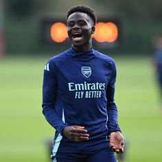 a soccer player smiles as he stands on the field