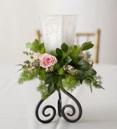 a vase with flowers and greenery is on a white table cloth covered tablecloth