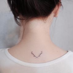 a woman's back neck with a small floral tattoo on the left side of her neck