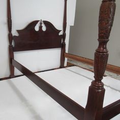 a wooden bed frame with white sheets and pillows