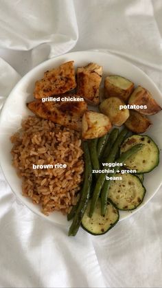 a white plate topped with rice and veggies next to fried chicken on top of brown rice