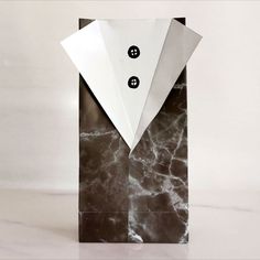 a black and white paper bag with buttons on it's side, sitting on a marble surface