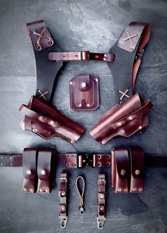 the leather holsters are laid out on the floor with their straps pulled back and fastened together