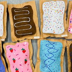 six decorated cookies are sitting on brown paper and placed in different shapes, sizes and colors