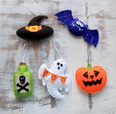 three halloween ornaments hanging from strings on a wooden surface, one with a bottle and the other with a bat