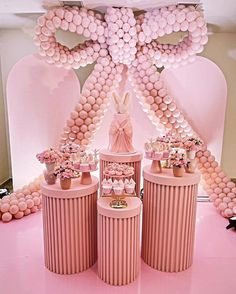 a pink table topped with vases filled with flowers next to balloons and bunnies