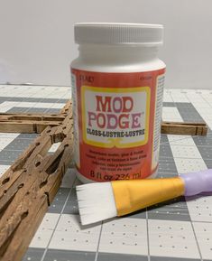 a bottle of mod podge next to a paintbrush and some wood planks