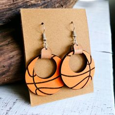 Get ready to show off your game day spirit with these Basketball Hoop Earrings! Cheer on your team in style with these stylish and fun earrings. Hand painted and made to order. Featuring metal findings and leather accents. ﻿This is a final sale item. It cannot be returned or exchanged. Basketball Earrings Diy, Basketball Earrings, Earrings Wood, Wild Orchid, Basketball Hoop, Paper Jewelry, Leather Accents, Hand Painted Wood, Fun Earrings