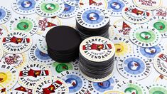 several stacks of black plastic coasters on top of a table covered in stickers