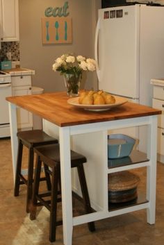 a kitchen island with two stools in front of it and a bowl of food on top