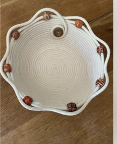 a white rope tray with red and orange glass beads on the bottom, sitting on a wooden floor