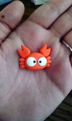 a hand holding an orange plastic crab on it's palm with its eyes wide open