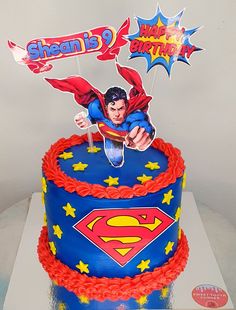 a superman birthday cake is decorated with red and blue icing