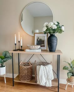 a wooden table topped with two baskets filled with flowers and candles next to a mirror