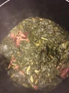 a pot filled with greens and meat on top of a stove