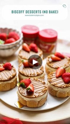 small desserts are arranged on a white platter with strawberries in the middle