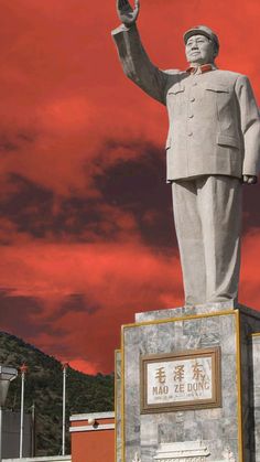 a large statue of mao zedong in front of a red sky