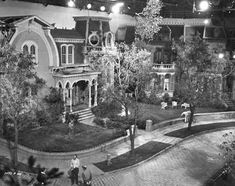 an old black and white photo of people walking in front of a house at night