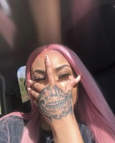 a woman with pink hair and tattoos covering her face