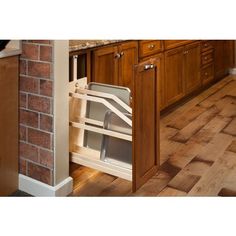 an open dishwasher in a kitchen next to a brick wall and wooden floors